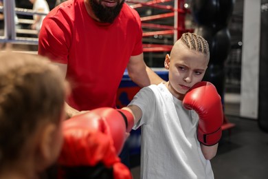 Children having boxing practice with their coach in training center