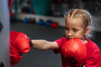 Girl in protective gloves having boxing practice indoors