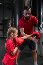 Boxing coach training girl in sport center