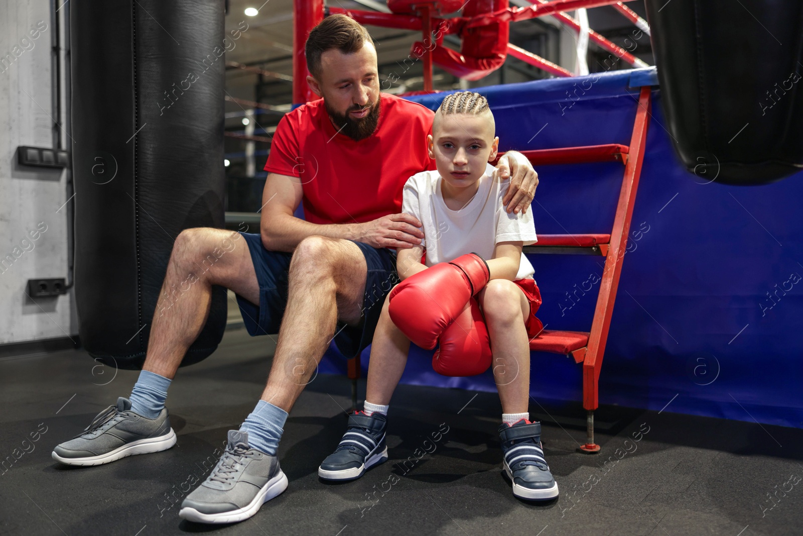 Photo of Coach comforting sad boy near boxing ring