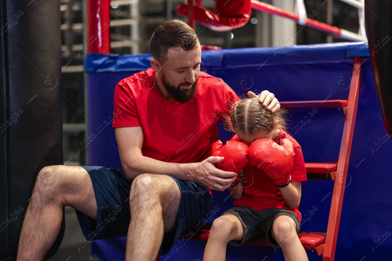 Photo of Coach comforting sad girl near boxing ring