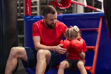 Coach comforting sad girl near boxing ring