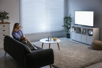 Woman watching tv on couch at home