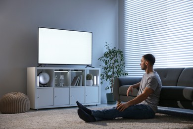 Photo of Man watching tv on floor at home