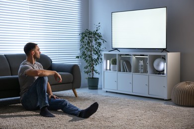 Photo of Man watching tv on floor at home