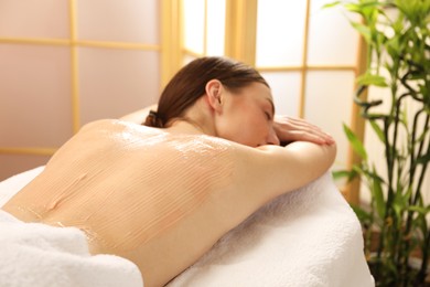 Woman undergoing body wraps treatment in spa salon