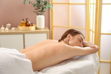 Woman undergoing body wraps treatment in spa salon