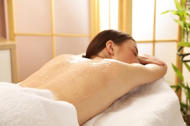 Woman undergoing body wraps treatment in spa salon