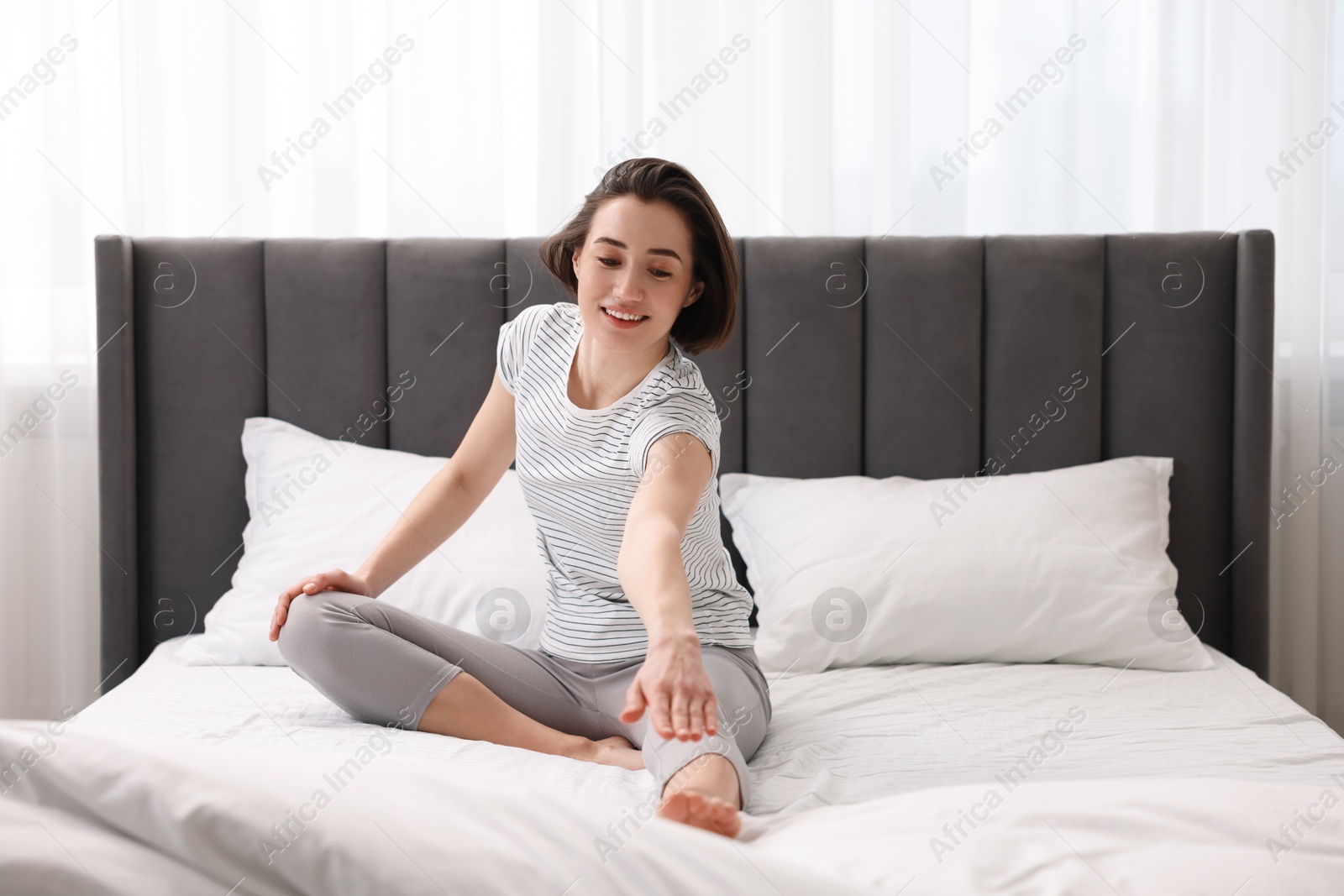 Photo of Young woman exercising on bed at home. Morning routine