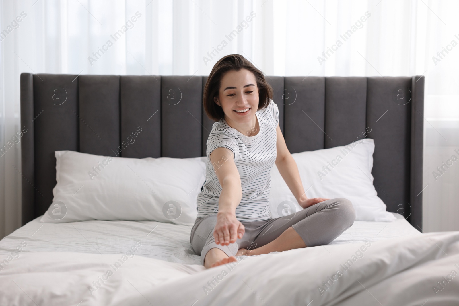 Photo of Young woman exercising on bed at home. Morning routine