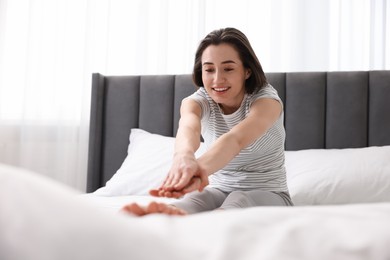 Young woman exercising on bed at home. Morning routine