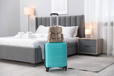 Photo of Stylish suitcase with backpack in hotel room