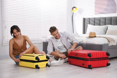 Happy couple unpacking their suitcases in hotel room