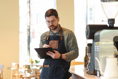 Handsome business owner working with clipboard in his cafe