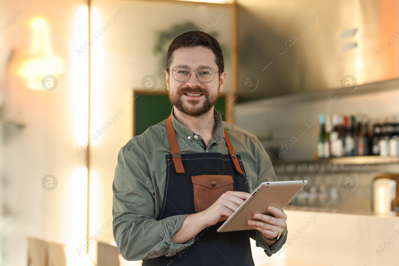 Photo of Portrait of smiling business owner with tablet in his cafe