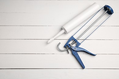 Photo of Glue gun and tube on white wooden background, flat lay. Space for text