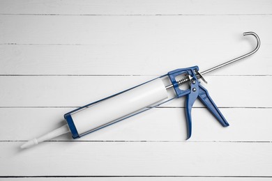 One glue gun on white wooden background, top view