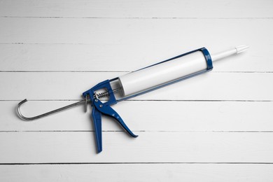 One glue gun on white wooden background, top view