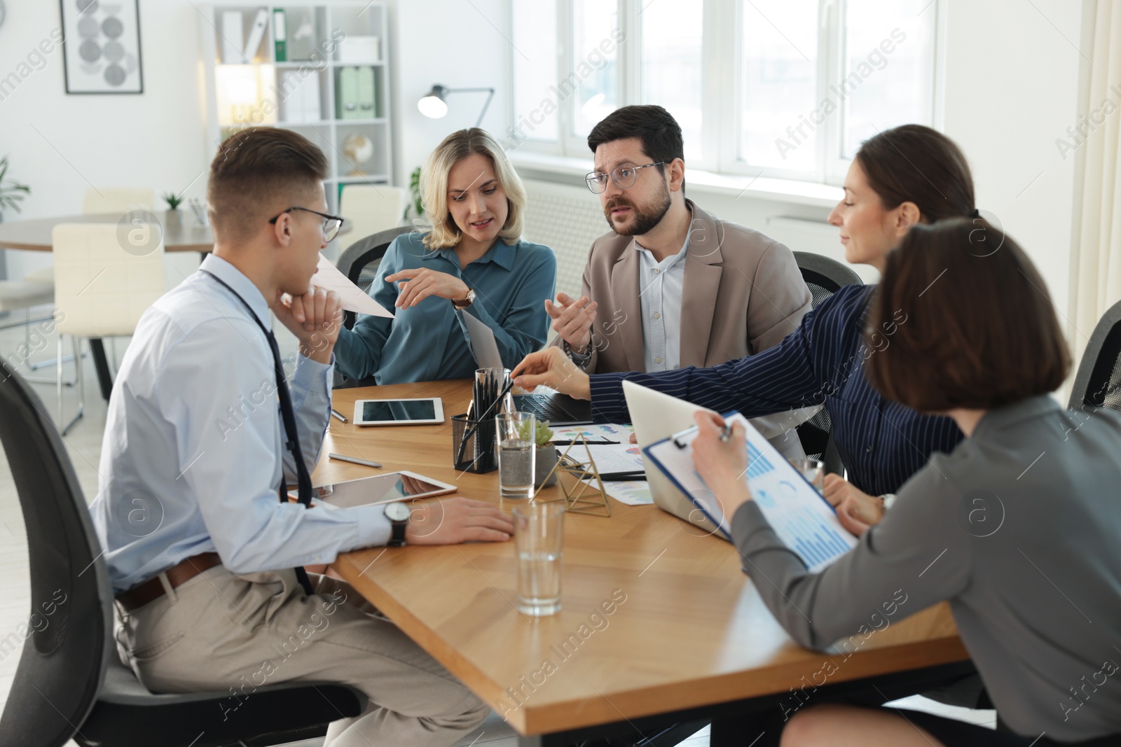 Photo of Coworkers working together at wooden table in office