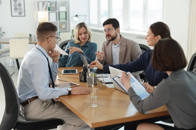 Coworkers working together at wooden table in office