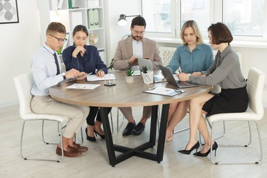 Coworkers working together at wooden table in office