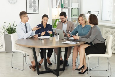 Coworkers working together at wooden table in office