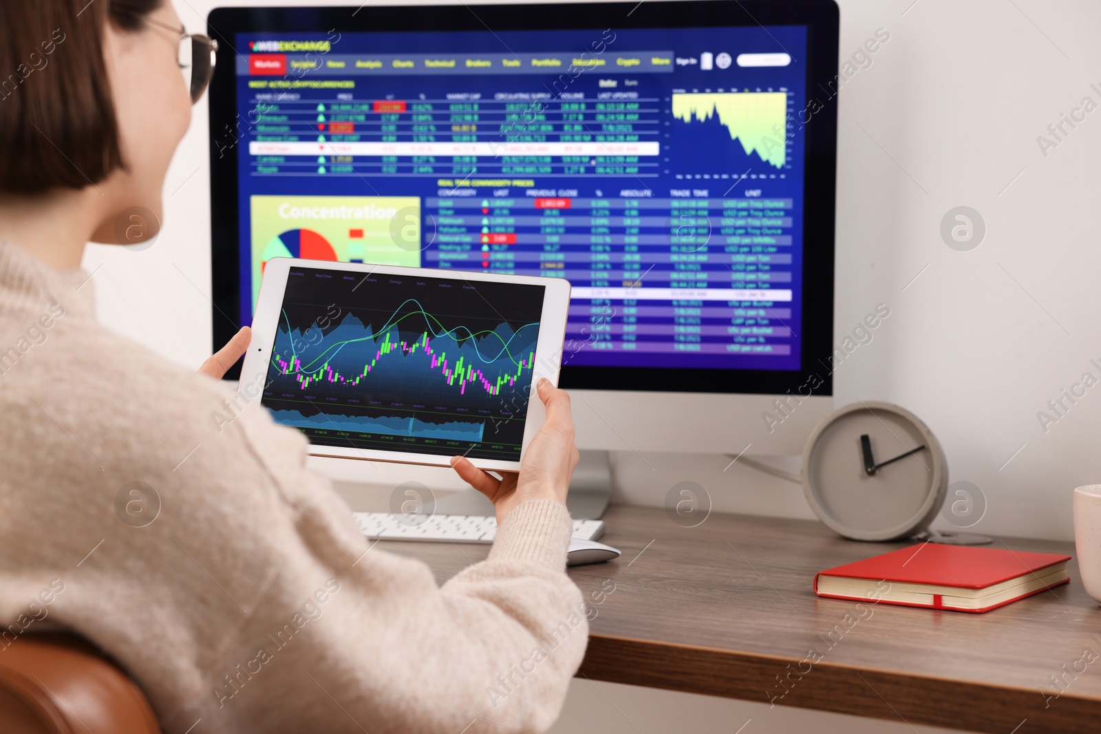 Photo of Stock exchange. Woman analysing financial market on tablet at wooden table indoors, closeup