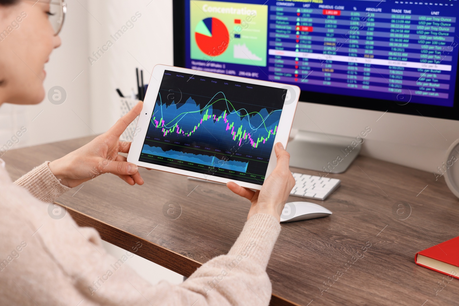 Photo of Stock exchange. Woman analysing financial market on tablet at wooden table indoors, closeup