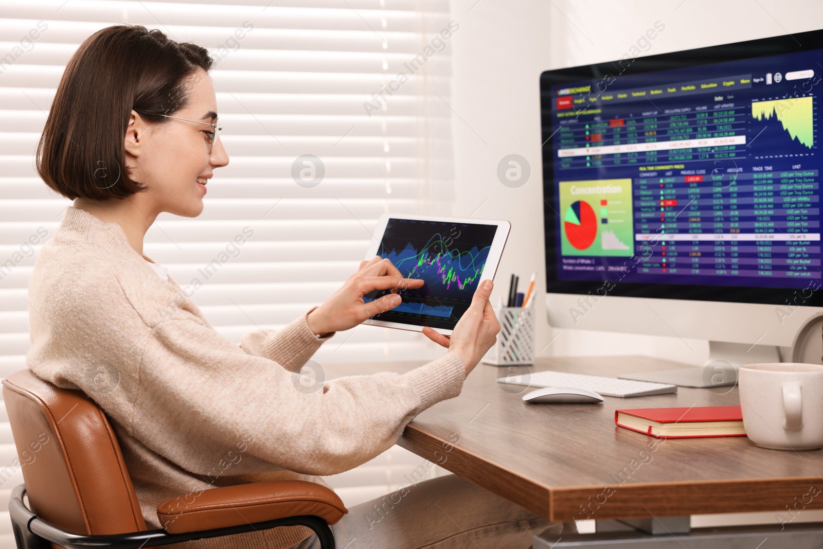 Photo of Stock exchange. Woman analysing financial market on tablet at wooden table indoors