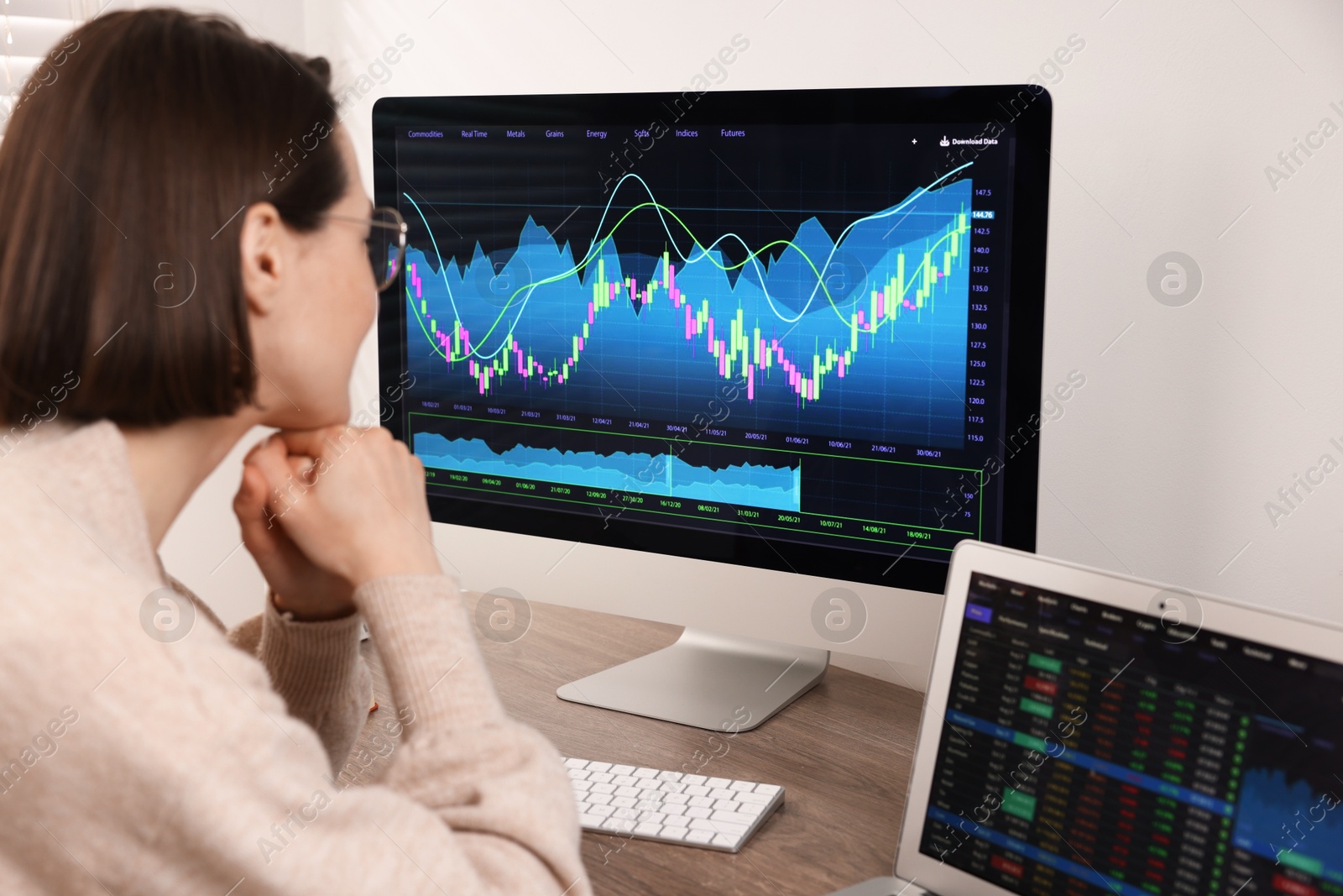 Photo of Stock exchange. Woman analysing financial market on computer at wooden table indoors