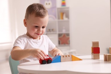 Photo of Motor skills development. Little boy playing with toys at white table indoors