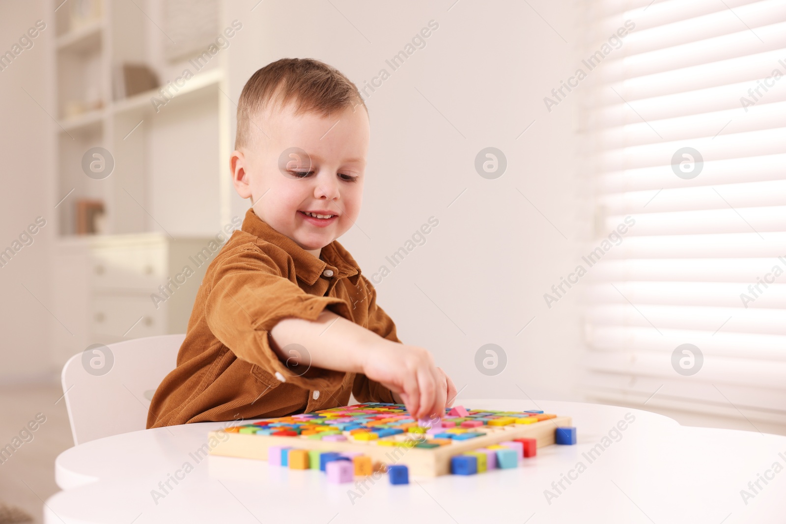 Photo of Motor skills development. Little boy playing with Times table tray indoors, space for text