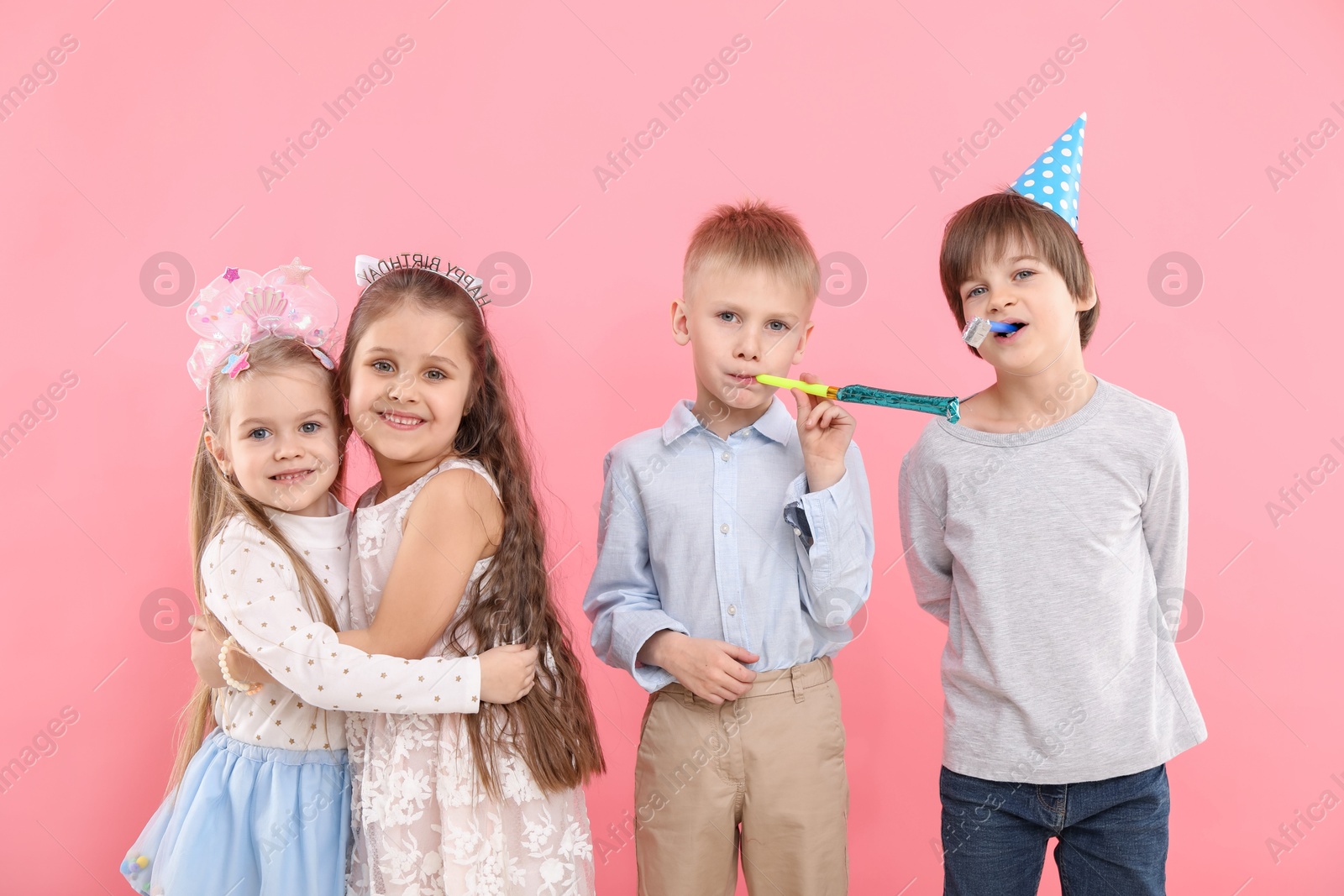 Photo of Children with blowers on pink background. Birthday surprise party