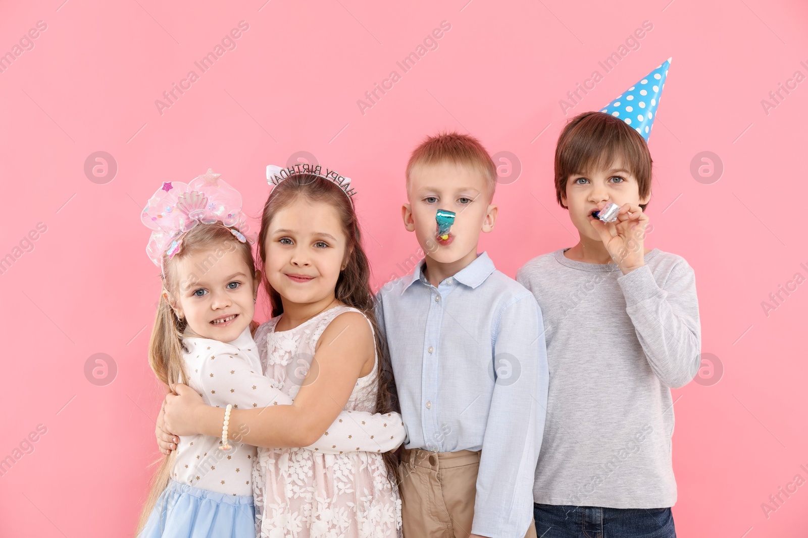 Photo of Children with blowers on pink background. Birthday surprise party