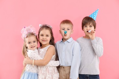 Photo of Children with blowers on pink background. Birthday surprise party