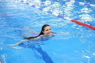 Beautiful young woman swimming in indoor pool