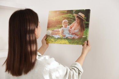 Photo of Canvas print. Woman hanging photo on wall at home