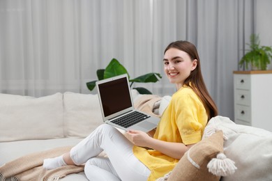 Photo of Smiling young woman working on laptop at home