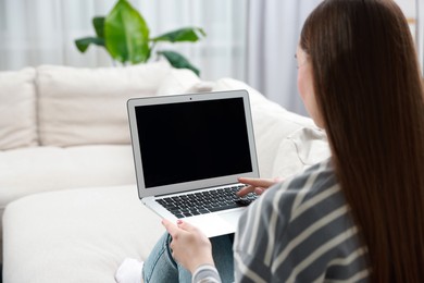 Young woman using laptop on sofa at home