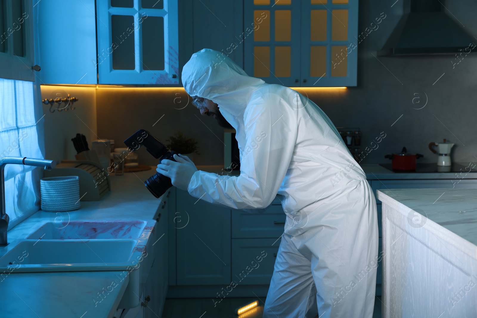 Photo of Forensic expert with camera working at crime scene indoors