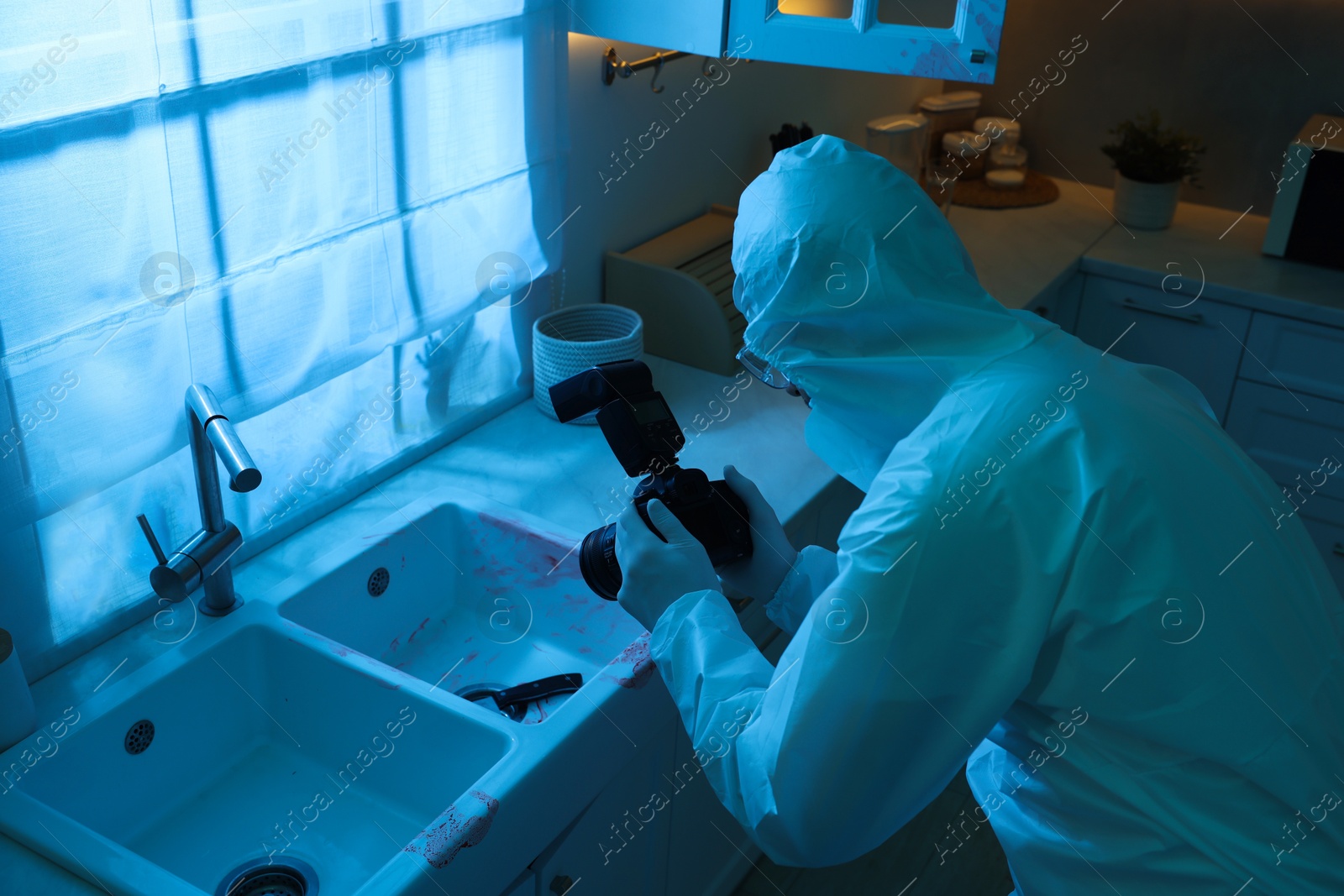 Photo of Forensic expert with camera working at crime scene indoors