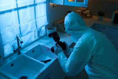 Photo of Forensic expert with camera working at crime scene indoors