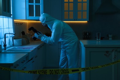 Photo of Forensic expert with camera working at crime scene indoors