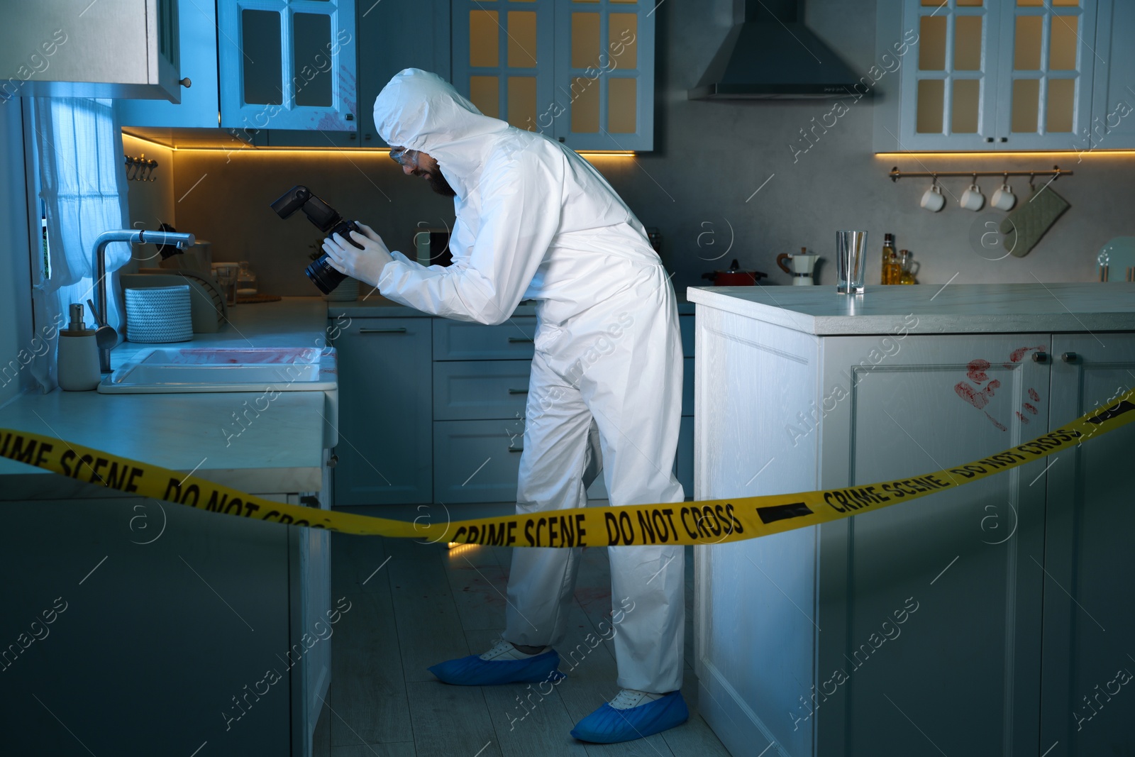 Photo of Forensic expert with camera working at crime scene indoors