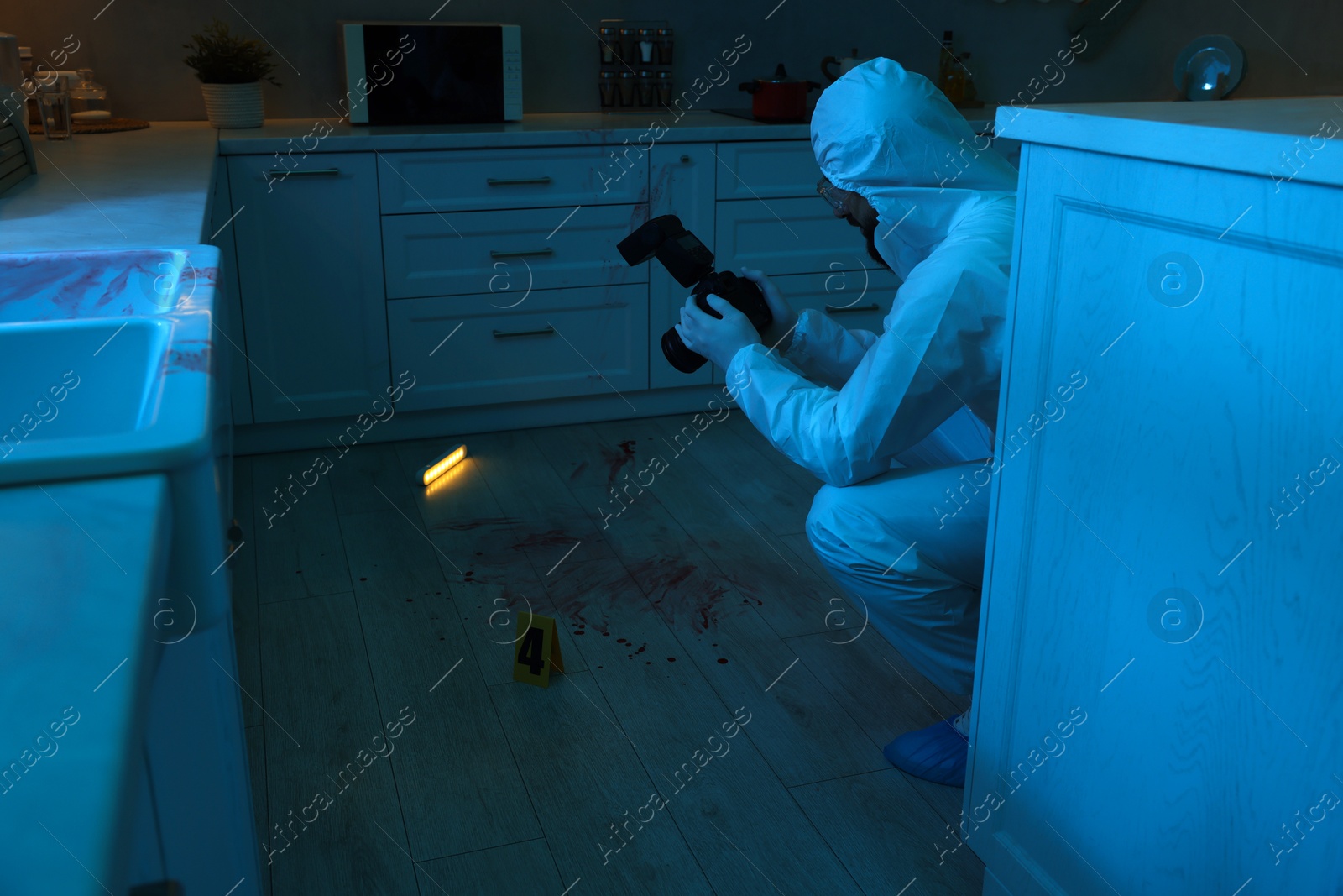 Photo of Forensic expert with camera working at crime scene indoors