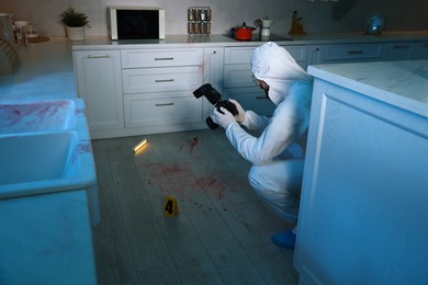 Photo of Forensic expert with camera working at crime scene indoors