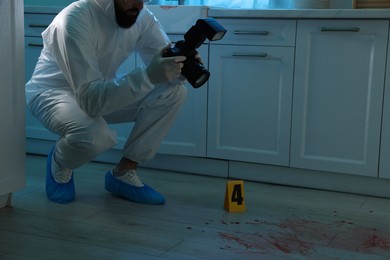 Forensic expert with camera working at crime scene indoors, closeup