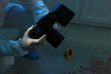 Forensic expert with camera working at crime scene indoors, closeup