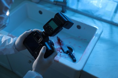 Forensic expert with camera working at crime scene indoors, closeup