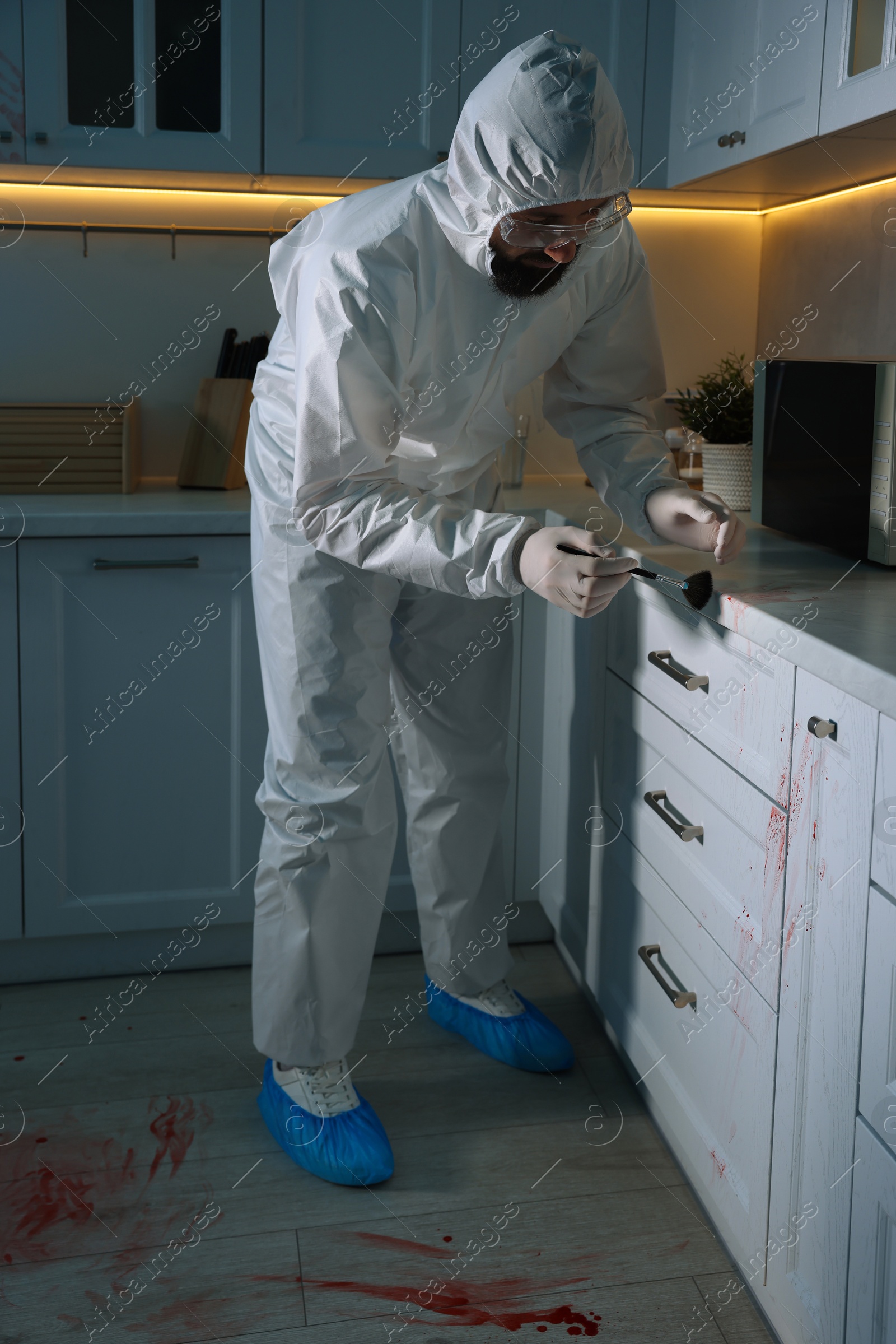 Photo of Forensic expert taking fingerprints from countertop with brush at crime scene indoors